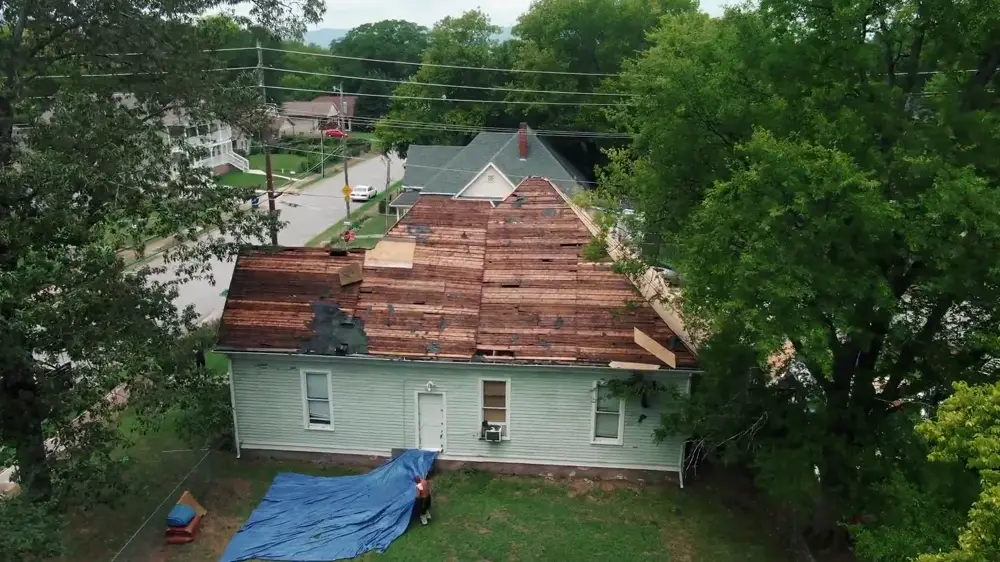 Drone view of a roof replacement in progress, old shingles torn off down to the decking